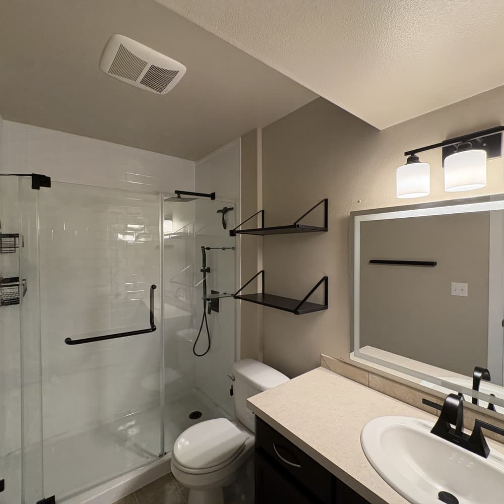 Finished bathroom with a frameless glass shower, black fixtures and new vanity