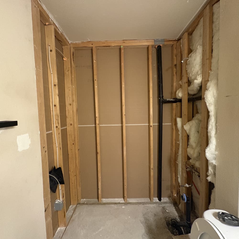 The same bathroom during demolition, stripped back to wall framing and plumbing